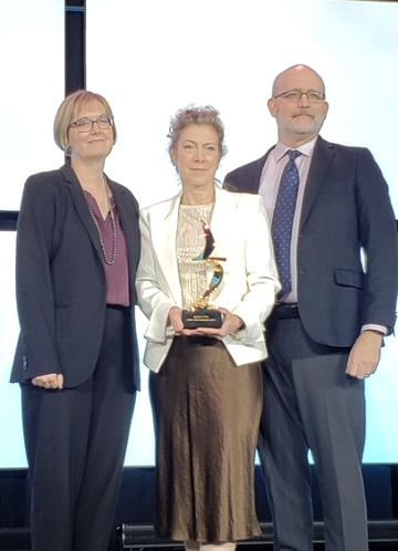 Ellen Taylor receives the FGI Pioneer Award from Heather Livingston and John Williams at the Healthcare Design + Expo Conference on November 6, 2023